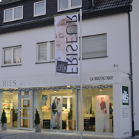 Eingangsportal mit durchgesteckten Buchstaben, Downlights und beleuchteten Logos.